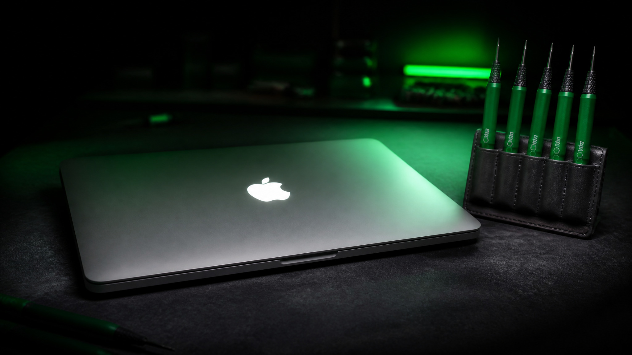 MacBook Pro with Apple logo glowing on lid as focal point and green Wiha precision drivers in tool holder
