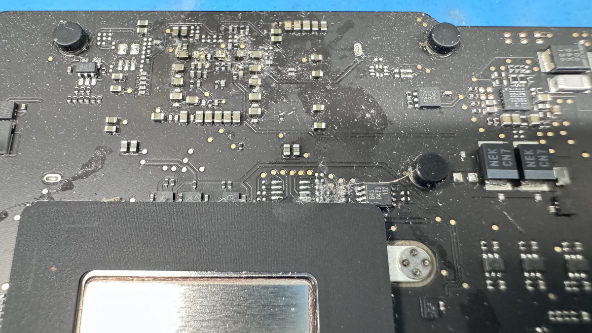Close-up of board-level component work being performed on an Apple Silicon MacBook logic board