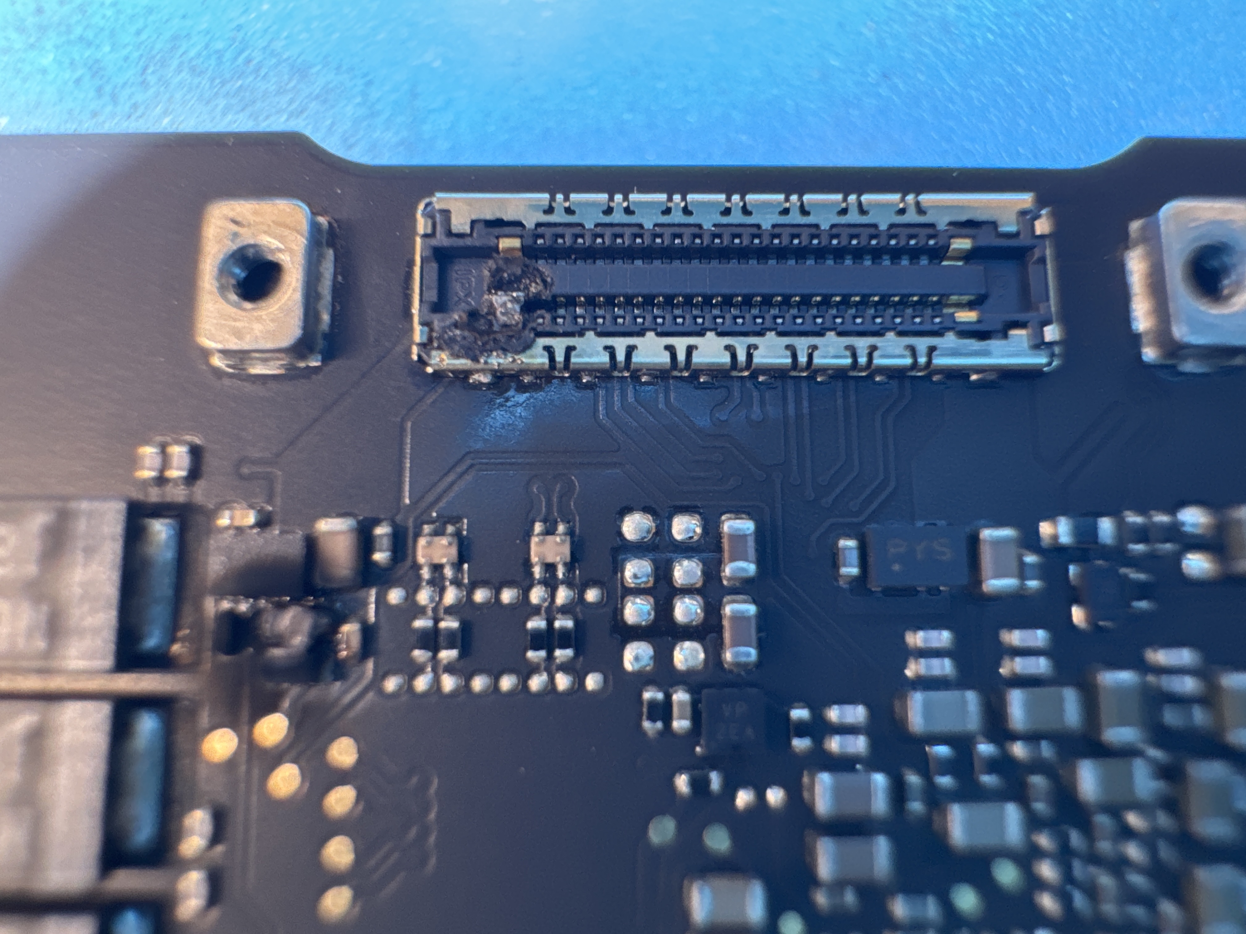 MacBook logic board connector and surface-mount components viewed under a microscope