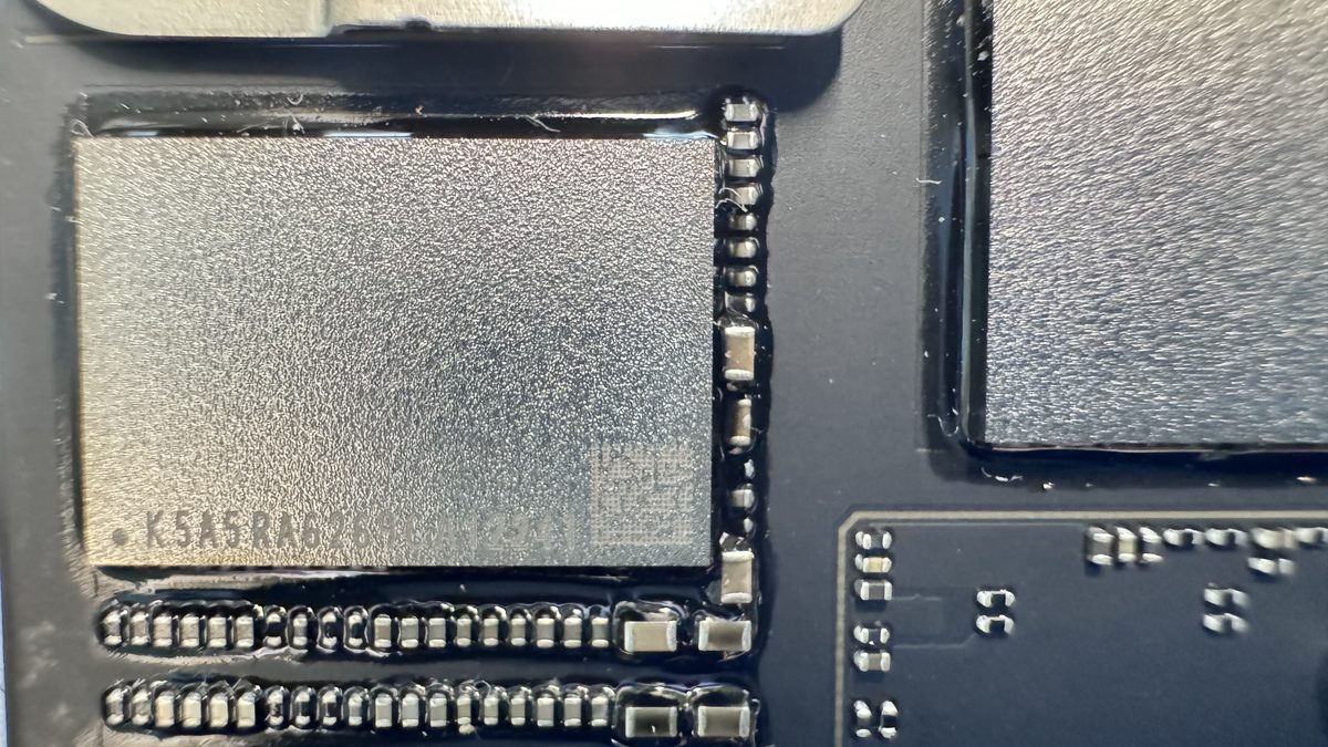 Close-up of a soldered SSD NAND flash chip on a MacBook logic board showing why data is tied to the board