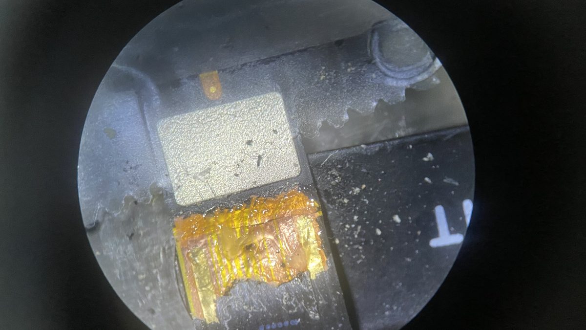 Microscope view of a MacBook Pro flex cable after replacement showing new copper traces soldered in place