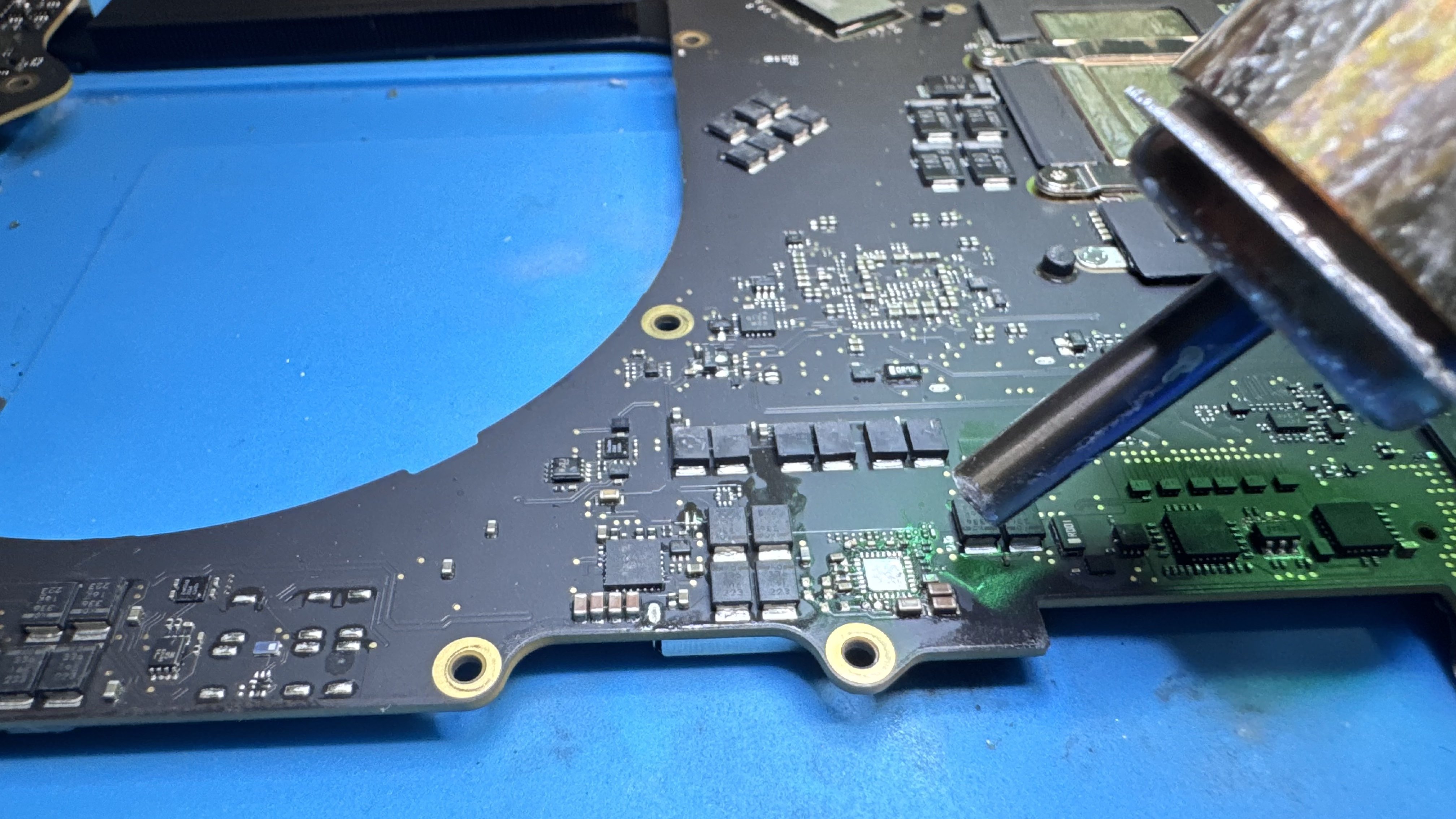 WarriorMac technician performing hot-air rework micro-soldering on a MacBook logic board