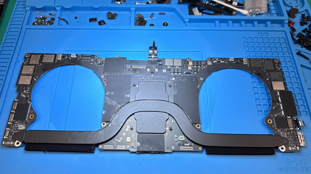 A MacBook Pro logic board removed and laid on a repair mat during a component-level T2 Mac repair