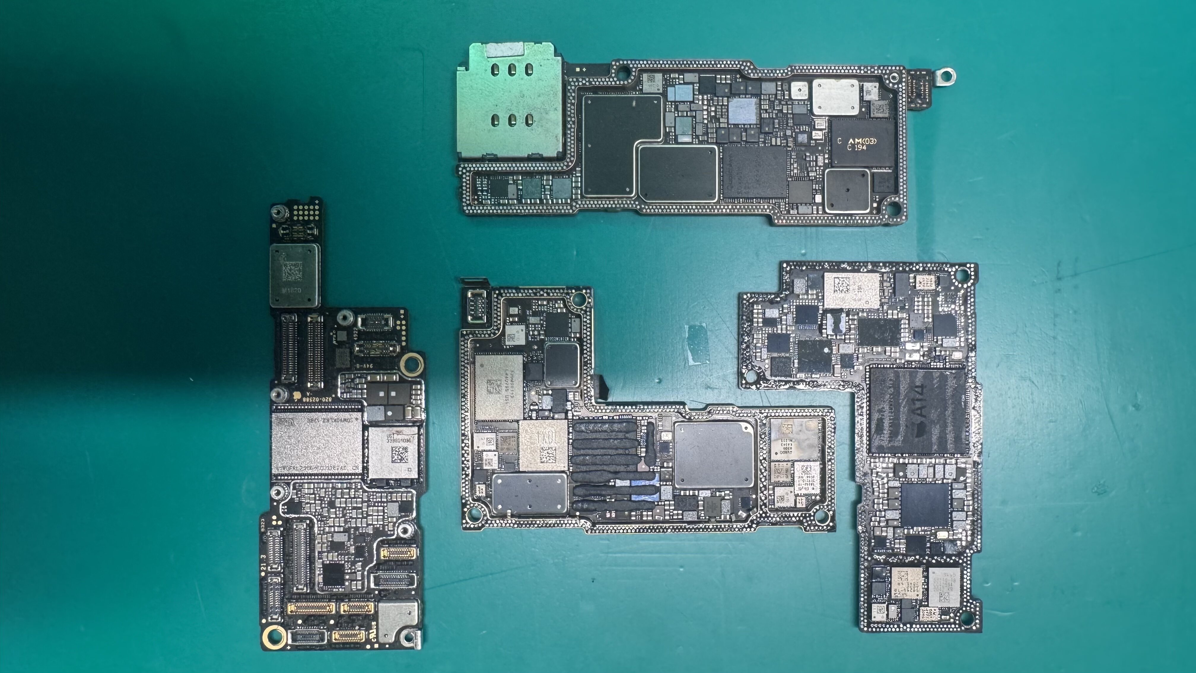 iPhone logic boards on green workbench at WarriorMac