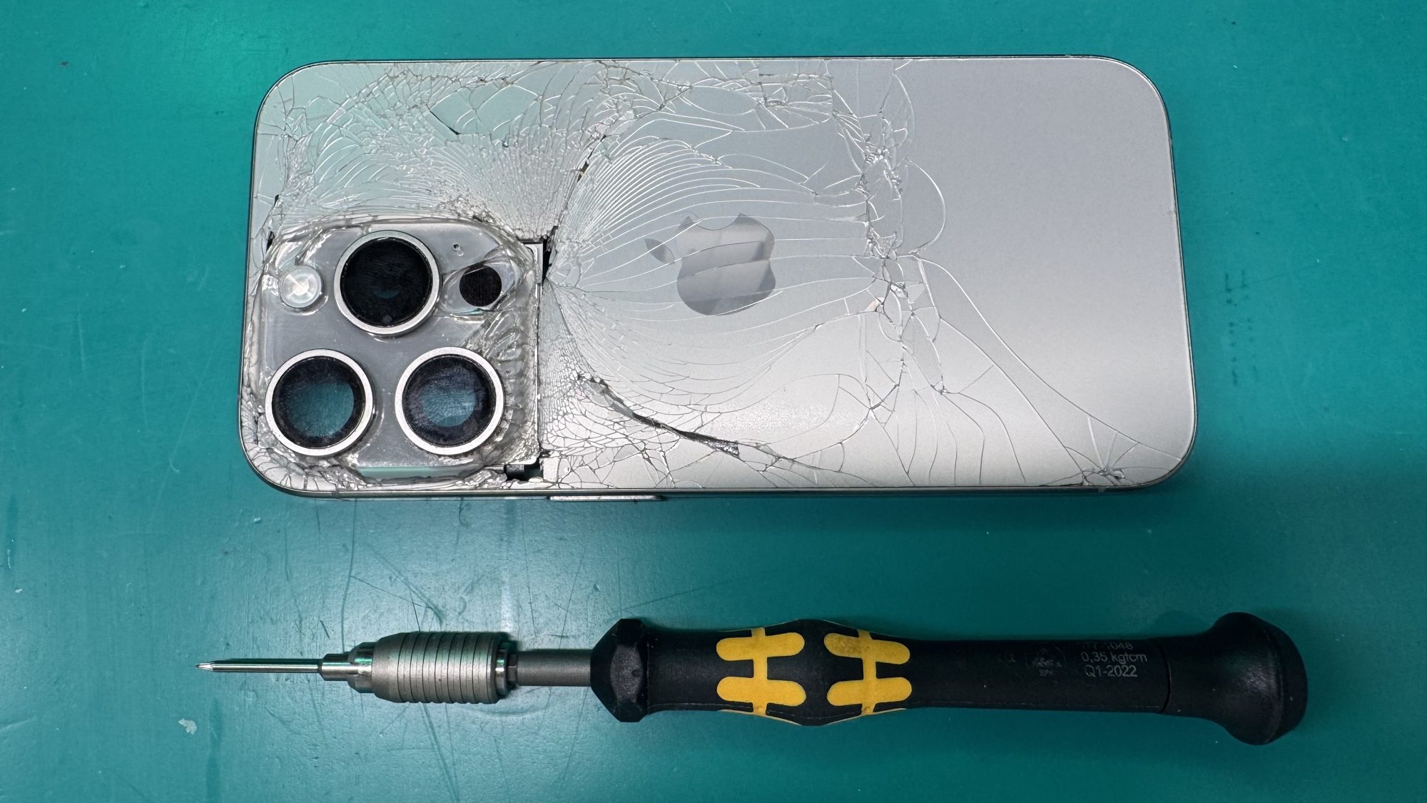 iPhone Pro with shattered back glass on the WarriorMac repair bench