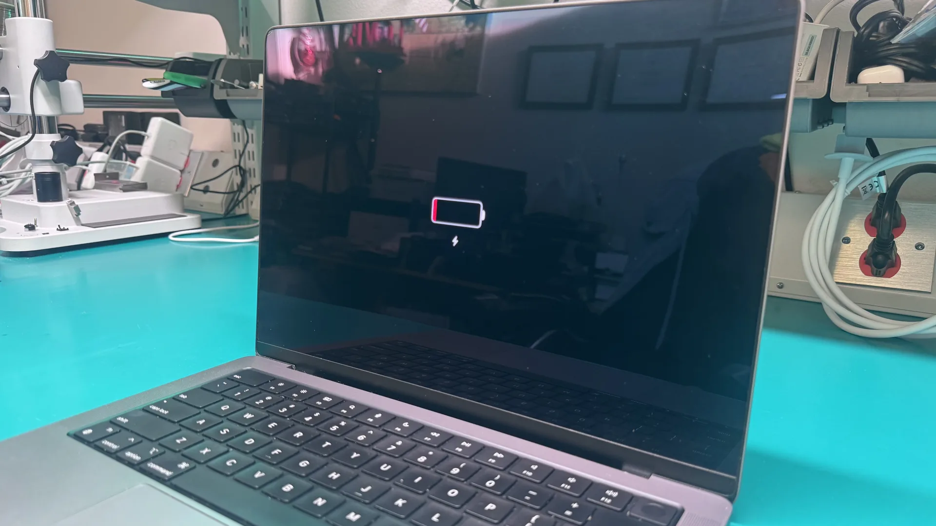 MacBook showing dead battery icon with charging indicator on screen at WarriorMac Tampa repair workbench