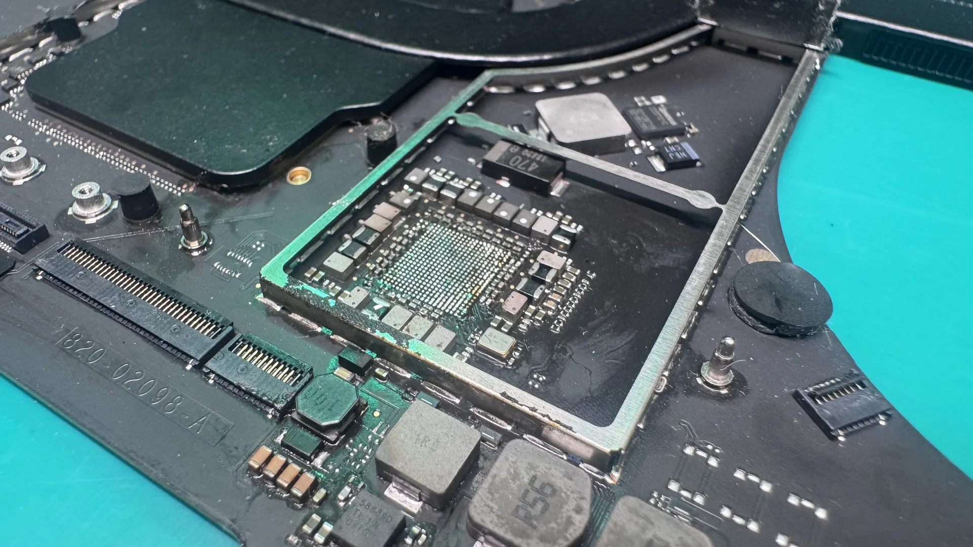 MacBook logic board with liquid damage corrosion under microscope at WarriorMac Tampa repair center