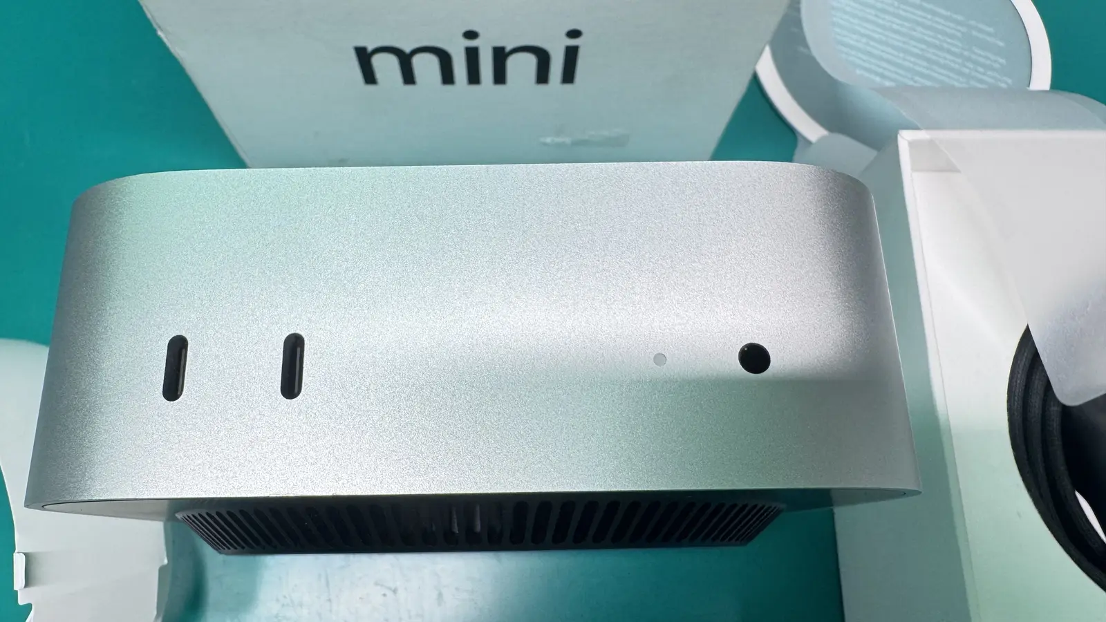 Mac Mini M4 front view showing USB-C ports and power indicator on WarriorMac green workbench