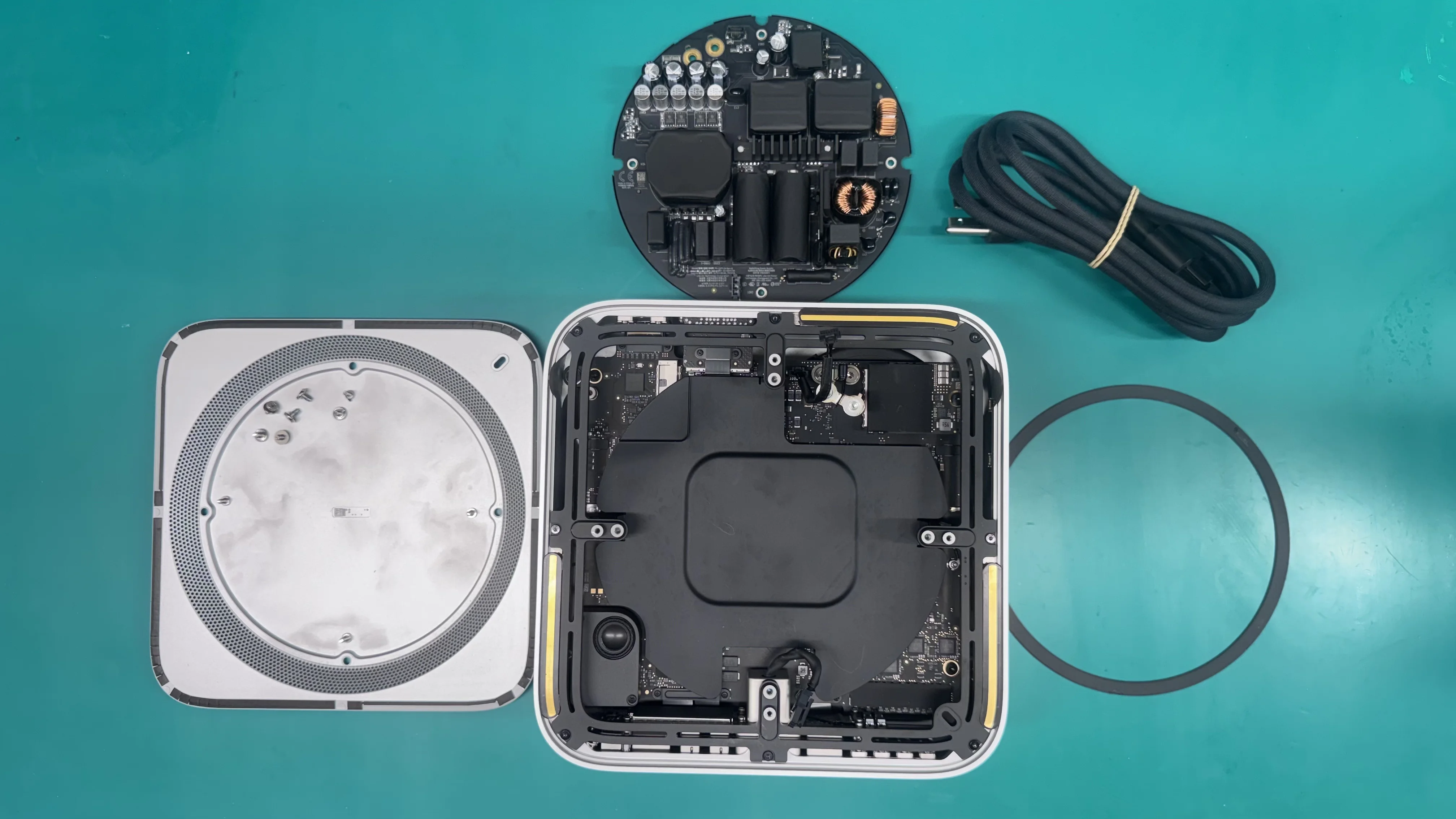 Mac Studio fully disassembled with power supply, logic board and power cable on WarriorMac repair workbench