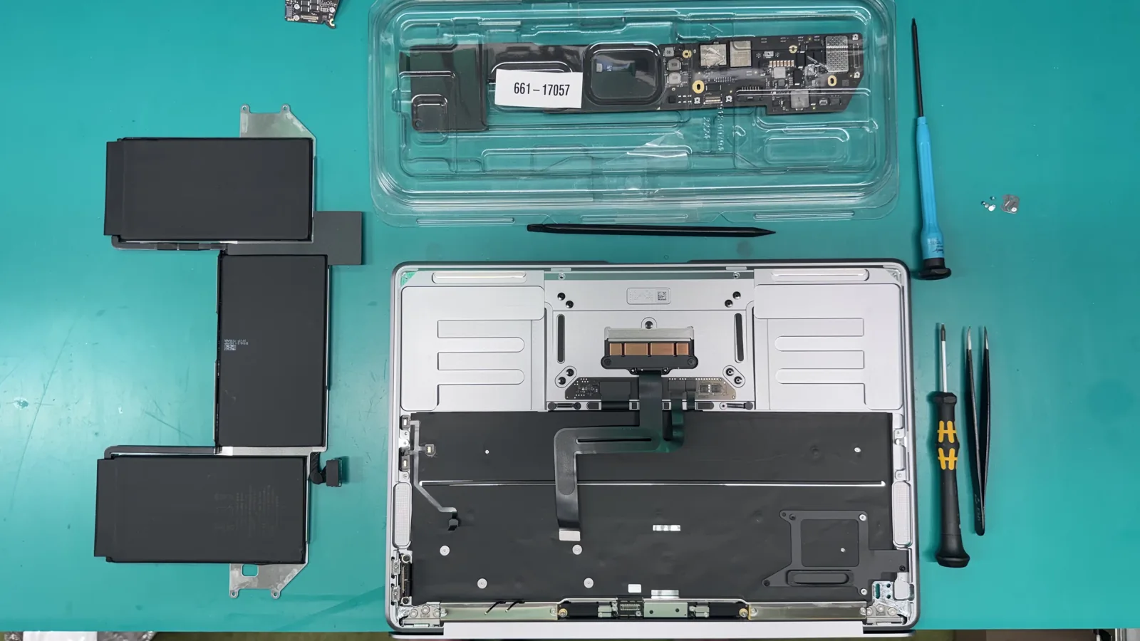 Old MacBook Air M1 battery cells removed and laid out beside the top case during the battery replacement at WarriorMac Tampa