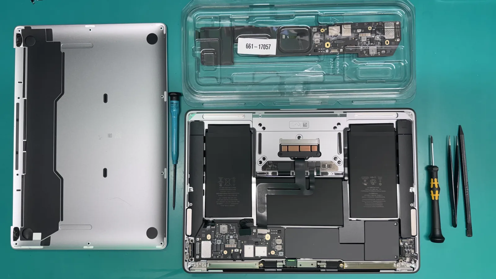 Genuine Apple MacBook Air M1 logic board, Apple service part 661-16819, in its sealed anti-static tray next to the opened laptop