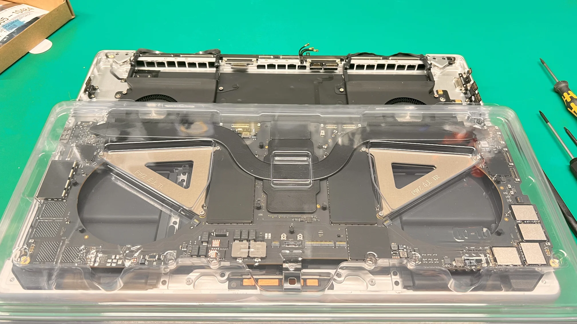 MacBook Pro logic board with dual heat sinks and cooling system exposed during repair at WarriorMac Tampa