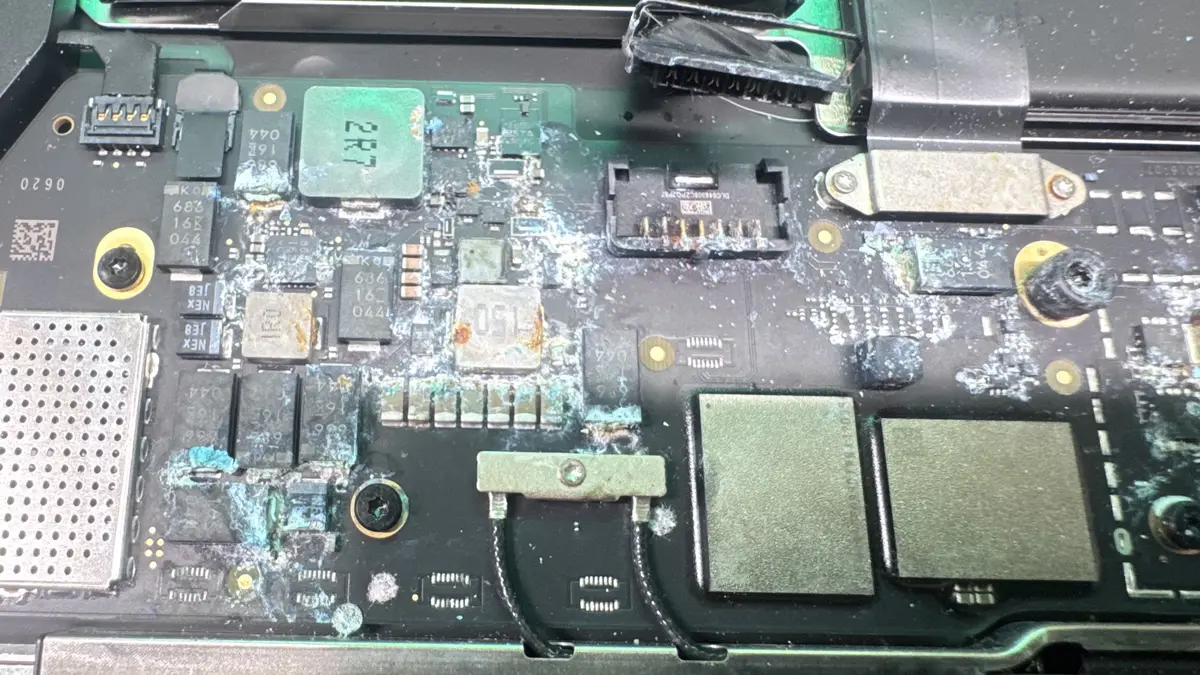 Close-up of corroded MacBook Pro logic board showing liquid damage on components