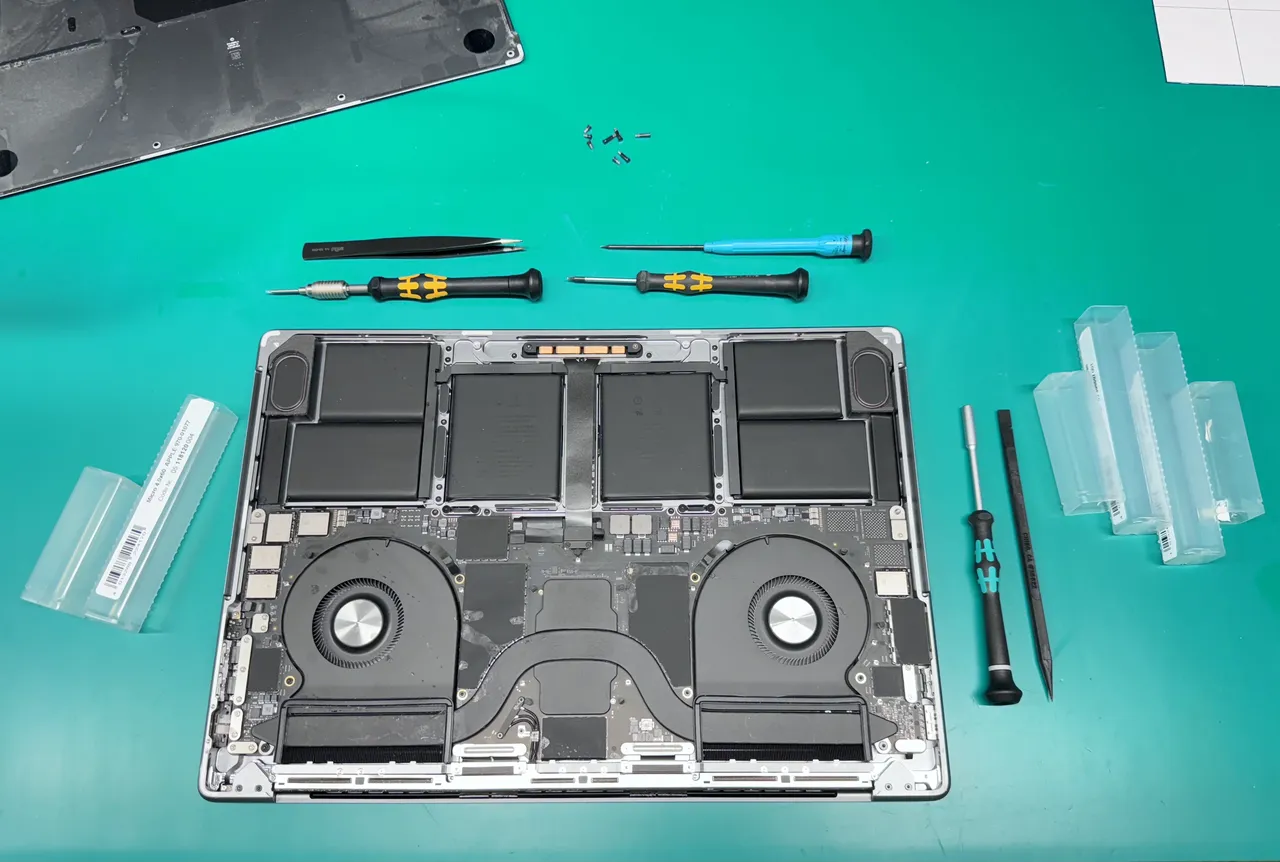 Mac repair diagnostics workstation at WarriorMac Tampa with precision tools and open laptop showing internal components