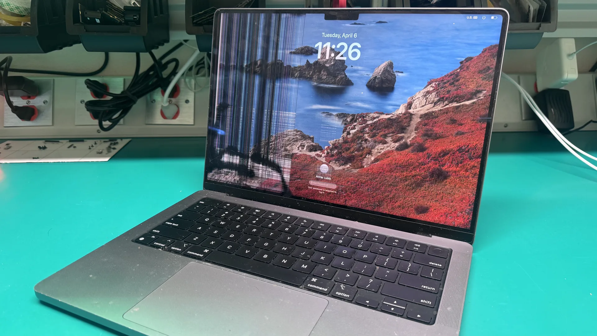 MacBook Pro with cracked and damaged LCD display showing distorted screen lines at WarriorMac Tampa repair workbench