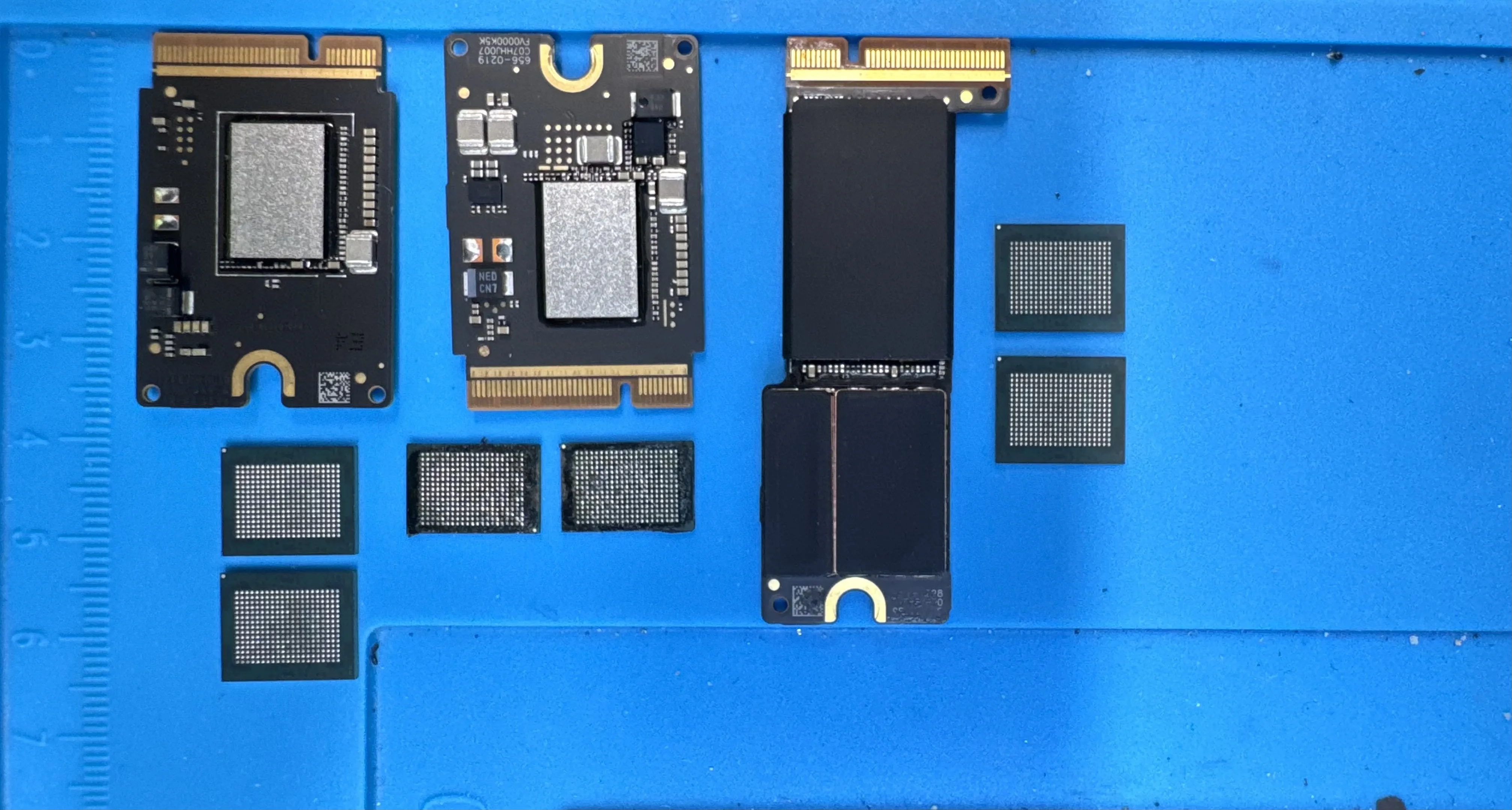 Multiple Mac SSD modules and NAND flash chips laid out on WarriorMac repair bench for storage upgrade service in Tampa