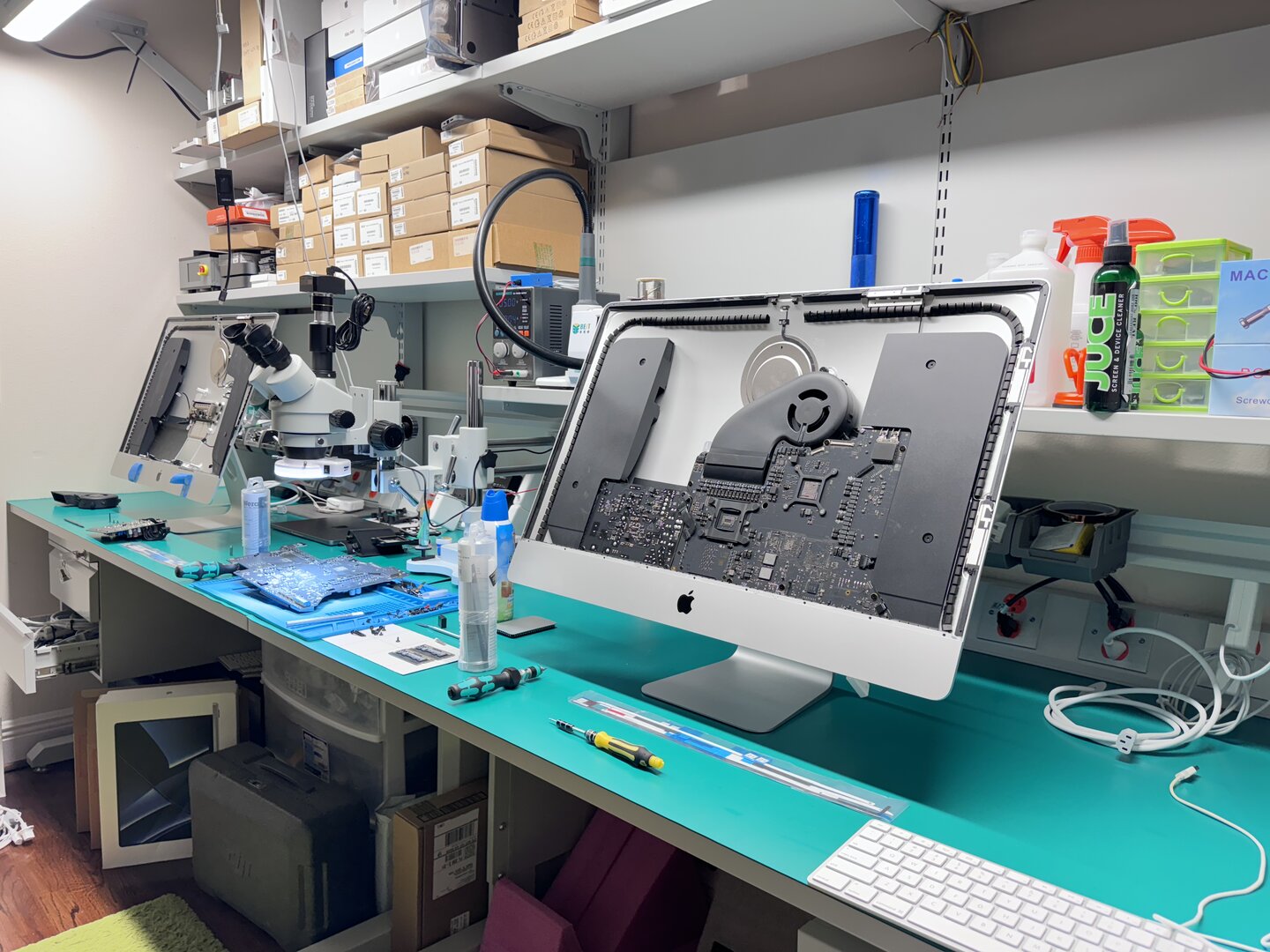 WarriorMac repair workbench, microscope, iMac with logic board exposed, and professional repair tools